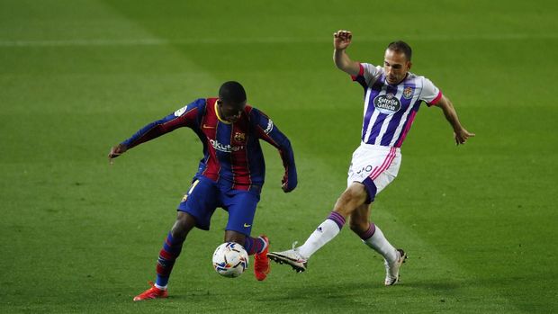 Barcelona's Ousmane Dembele, left, is challenged by Valladolid's Nacho during the Spanish La Liga soccer match between FC Barcelona and Valladolid CF at the Camp Nou stadium in Barcelona, Spain, Monday, April 5, 2021. (AP Photo/Joan Monfort)