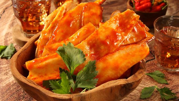 Keripik singkong balado Kripik Singkong Balado, the popular snack from Padang, West Sumatra. Thin, elongated slices of cassava coated with red chili sauce. Plated in a wooden bowl and garnished with celery leaves.