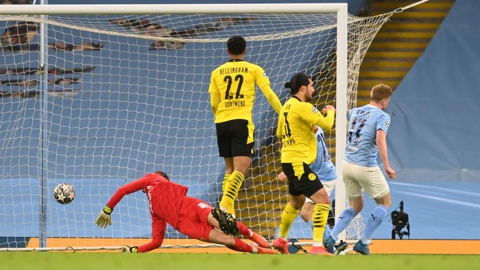 MANCHESTER, ENGLAND - APRIL 06: Kevin De Bruyne of Manchester City scores their teams first goal under pressure from Emre Can of Borussia Dortmund during the UEFA Champions League Quarter Final match between Manchester City and Borussia Dortmund at Manchester City Football Academy on April 06, 2021 in Manchester, England. Sporting stadiums around the UK remain under strict restrictions due to the Coronavirus Pandemic as Government social distancing laws prohibit fans inside venues resulting in games being played behind closed doors.  (Photo by Michael Regan/Getty Images)
