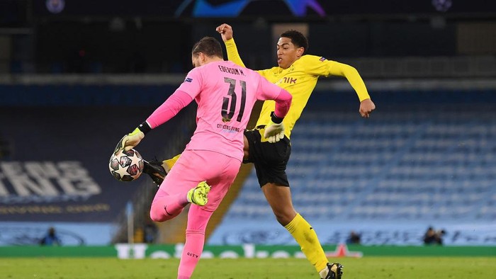 MANCHESTER, ENGLAND - APRIL 06: Jude Bellingham of Borussia Dortmund tackles Ederson of Manchester City to win the ball during the UEFA Champions League Quarter Final match between Manchester City and Borussia Dortmund at Etihad Stadium on April 06, 2021 in Manchester, England. Sporting stadiums around the UK remain under strict restrictions due to the Coronavirus Pandemic as Government social distancing laws prohibit fans inside venues resulting in games being played behind closed doors. (Photo by Michael Regan/Getty Images)