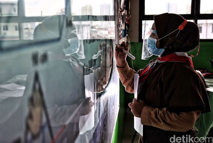 Guru memberikan pelajaran kepada murid saat uji coba belajar tatap muka di kawasan SDN 11 Pademangan Barat, Jakarta Utara, Rabu (7/4). SDN Pademangan Barat 11 memulai uji coba belajar tatap muka bagi siswa kelas V di tengah pandem COVID-19. Protokol kesehatan menjadi hal utama baik bagi siswa maupun tenaga pendidik.