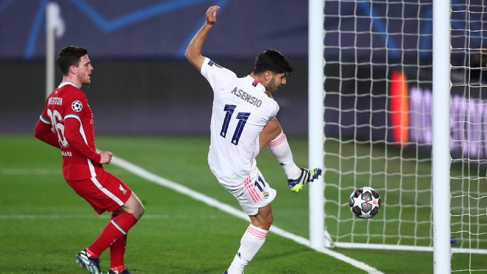 MADRID, SPAIN - APRIL 06: Marco Asensio of Real Madrid scores their teams second goal while pressured by Andrew Robertson of Liverpool during the UEFA Champions League Quarter Final match between Real Madrid and Liverpool FC at Estadio Alfredo Di Stefano on April 06, 2021 in Madrid, Spain. Sporting stadiums around Spain remain under strict restrictions due to the Coronavirus Pandemic as Government social distancing laws prohibit fans inside venues resulting in games being played behind closed doors.  (Photo by Fran Santiago/Getty Images)