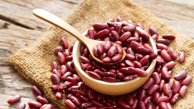 Red bean on wooden bowl with spoon and linen background top view