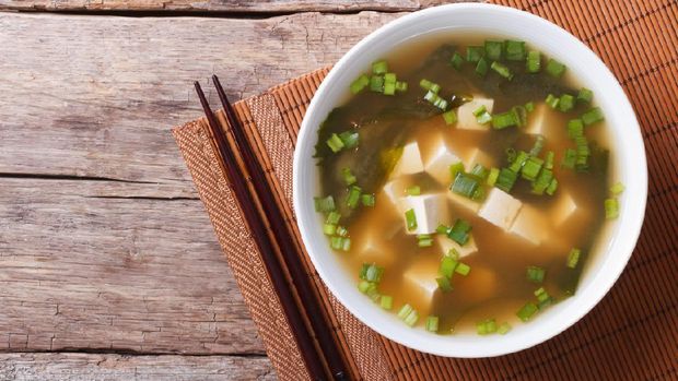 Japanese miso soup in a white bowl on the table. horizontal view from above