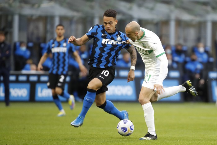 Inter Milans Lautaro Martinez, left, fights for the ball with Sassuolos Vlad Chiriches during the Serie A soccer match between Inter Milan and Sassuolo at the San Siro Stadium in Milan, Italy, Wednesday, April 7, 2021. (AP Photo/Antonio Calanni)