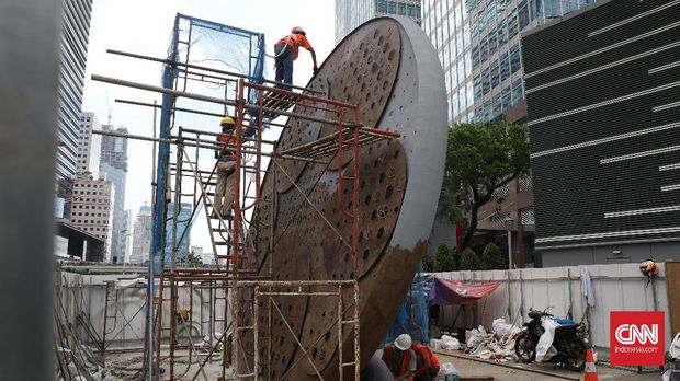 Pekerja menyelesaikan pembangunan Tugu Sepeda di Jalan Jenderal Sudirman, Jakarta, Kamis, 8 April 2021. Pembangunan tugu yang berbentuk satu buah ban sepeda berukuran raksasa tersebut sebagai pengingat momentum penggunaan sepeda yang masif digunakan masyarakat ibu kota pada masa pandemi covid 19. CNNIndonesia/Safir Makki