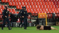 Pria bugil tersebut berlari-lari dan langsung rebahan di lapangan. (Foto: Cristina Quicler/AFP/Edit)