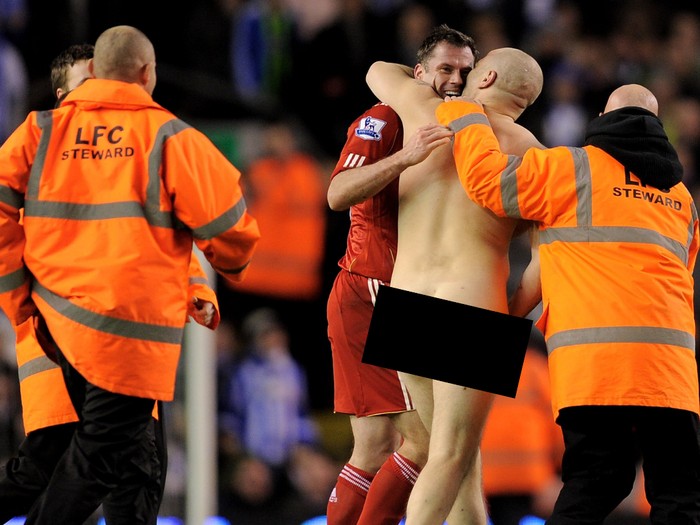 LIVERPOOL, ENGLAND - FEBRUARY 19: Jamie Carragher of Liverpool helps to escort a streaker from the pitch during the FA Cup Fifth Round match between Liverpool and Brighton & Hove Albion at Anfield on February 19, 2012 in Liverpool, England. (Photo by Michael Regan/Getty Images)