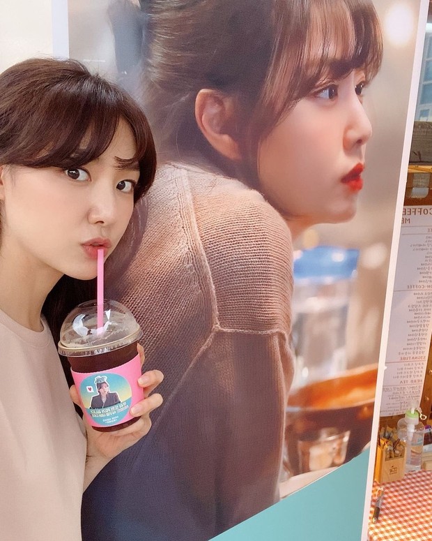 Seo Ji Hye/instagram.com/jihye8024 Seo Ji Hye sedang minum dekat banner fotonya/instagram.com/jihye8024