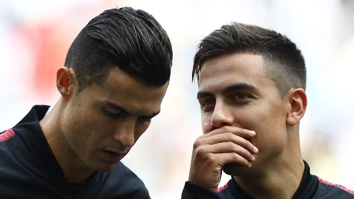 Paulo Dybala menutupi mulutnya saat bicara dengan Ronaldo. Kebiasaan pesepakbola menutupi mulut saat bicara diminta dihentikan. (Foto: Marco Luzzani/Getty Images)