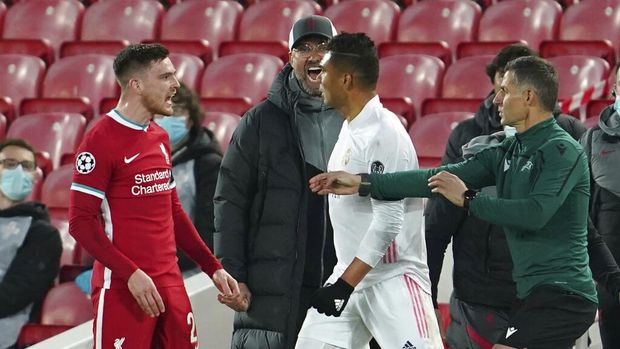 Liverpool's manager Jurgen Klopp, background, yells as Liverpool's Andrew Robertson, left, fights with Real Madrid's Casemiro during a Champions League quarter final second leg soccer match between Liverpool and Real Madrid at Anfield stadium in Liverpool, England, Wednesday, April 14, 2021. (AP Photo/Jon Super)