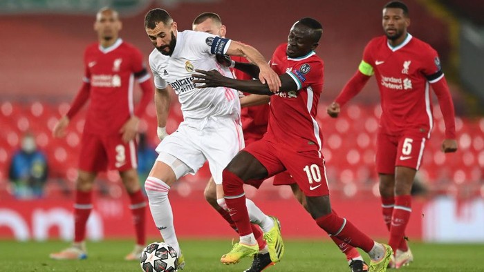 LIVERPOOL, ENGLAND - APRIL 14: Karim Benzema of Real Madrid is challenged by Sadio Mane of Liverpool during the UEFA Champions League Quarter Final Second Leg match between Liverpool FC and Real Madrid at Anfield on April 14, 2021 in Liverpool, England. Sporting stadiums around the UK remain under strict restrictions due to the Coronavirus Pandemic as Government social distancing laws prohibit fans inside venues resulting in games being played behind closed doors. (Photo by Shaun Botterill/Getty Images)