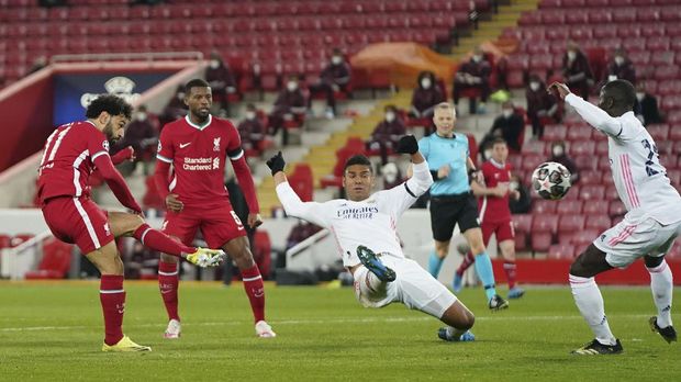 Liverpool's Mohamed Salah, left, attempts a shot at goal and misses in front of Real Madrid's Casemiro, center, and Real Madrid's Ferland Mendy, right, during a Champions League quarter final second leg soccer match between Liverpool and Real Madrid at Anfield stadium in Liverpool, England, Wednesday, April 14, 2021. (AP Photo/Jon Super)
