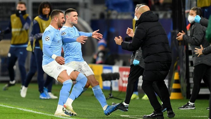 DORTMUND, GERMANY - APRIL 14: Phil Foden of Manchester City runs towards Pep Guardiola, Manager of Manchester City as he celebrates with team mate Kyle Walker after scoring their sides second goal during the UEFA Champions League Quarter Final Second Leg match between Borussia Dortmund and Manchester City at Signal Iduna Park on April 14, 2021 in Dortmund, Germany. Sporting stadiums around Germany remain under strict restrictions due to the Coronavirus Pandemic as Government social distancing laws prohibit fans inside venues resulting in games being played behind closed doors.  (Photo by Friedemann Vogel - Pool/Getty Images)