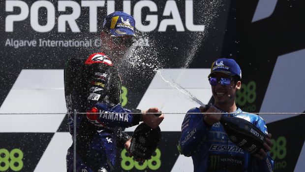 MotoGP - Portuguese Grand Prix - Algarve International Circuit, Portimao, Portugal - April 18, 2021 Monster Energy Yamaha MotoGP's Fabio Quartararo sprays champagne as he celebrates on the podium after winning the race alonside third placed Team Suzuki Ecstar's Joan Mir REUTERS/Pedro Nunes