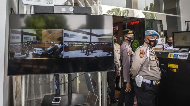 Petugas kepolisian berada di dekat layar yang menampilkan suasana sidang lanjutan kasus pelanggaran protokol kesehatan dengan terdakwa Rizieq Shihab di Pengadilan Negeri (PN) Jakarta Timur, Jakarta, Senin (19/4/2021). Sidang tersebut beragendakan pemeriksaan saksi yang dihadirkan Jaksa Penuntut Umum (JPU). ANTARA FOTO/Aprillio Akbar/hp.