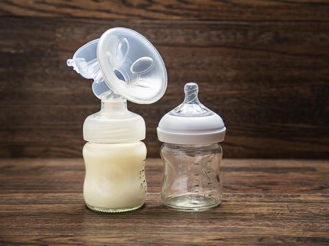 Baby bottle with breast pump attachement and empty bottle against a wood background