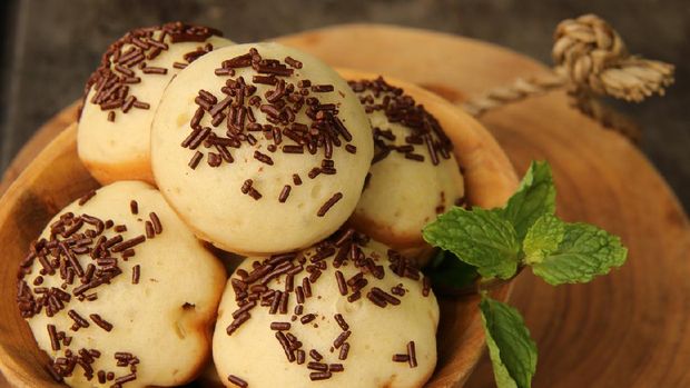 Kue Cubit, a popular street food and snack from Betawi, Jakarta. It is the Indonesian version of Dutch's poffertjes; with added topping of chocolate sprinkles instead of powder sugar. The kue cubit are arranged on a natural wooden bowl. A wooden block is used as the base; which then placed on a metal baking sheet.