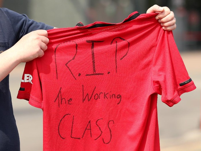 MANCHESTER, ENGLAND - APRIL 20: A Manchester United fan holds up a football shirt which reads 'R.I.P The Working Class' as they stand outside Old Trafford on April 20, 2021 in Manchester, England. Six English premier league teams have announced they are part of plans for a breakaway European Super League. Arsenal, Manchester United, Manchester City, Liverpool, Chelsea and Tottenham Hotspur will join 12 other European teams in a closed league similar to that of the NFL American Football League. In a statement released last night, the new competition 