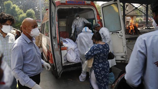 Gelombang Kedua Corona di India, Kremasi Mayat Operasi 24 Jam Health workers prepare to take out from an ambulance bodies of six people who died of COVID-19 for cremation, in New Delhi, India, Monday, April 19, 2021. New Delhi imposed a weeklong lockdown Monday night to prevent the collapse of the Indian capital's health system, which authorities said had been pushed to its limit amid an explosive surge in coronavirus cases. (AP Photo/Manish Swarup)