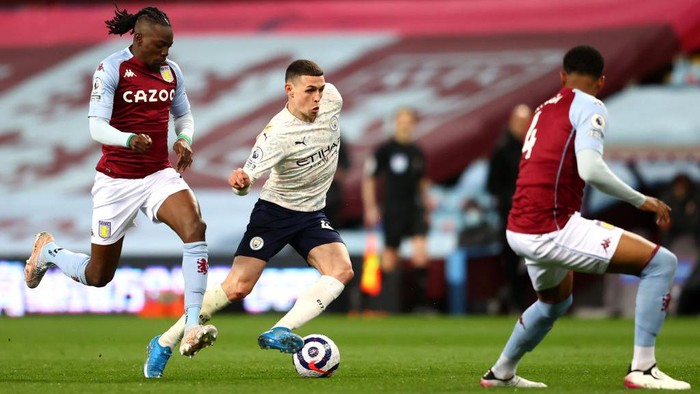 BIRMINGHAM, ENGLAND - APRIL 21: Phil Foden of Manchester City runs with the ball whilst under pressure from Bertrand Traore of Aston Villa during the Premier League match between Aston Villa and Manchester City at Villa Park on April 21, 2021 in Birmingham, England. Sporting stadiums around the UK remain under strict restrictions due to the Coronavirus Pandemic as Government social distancing laws prohibit fans inside venues resulting in games being played behind closed doors.  (Photo by Michael Steele/Getty Images)