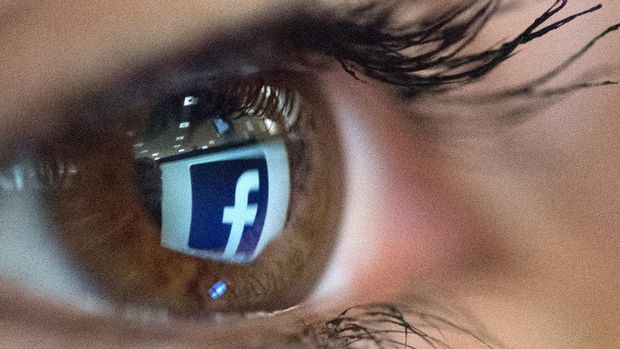 (FILES) In this file photo taken on April 14, 2021 an illustration picture taken in Paris shows a close-up of the Facebook logo in the eye of an AFP staff member posing while she looks at a flipped logo of Facebook. - Facebook said April 22, 2021 it would emphasize user feedback when prioritizing posts on the leading social network, the latest move to quell concerns over its algorithms. (Photo by Christophe SIMON / AFP)