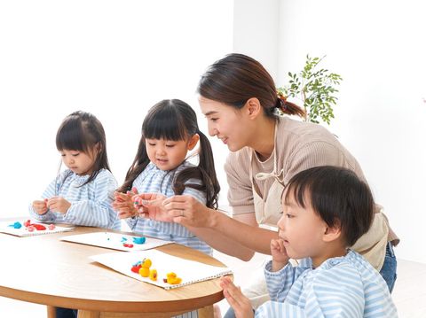 Asian kindergarten student girl with mother painting picture in book with color pencil at home, Homeschooling and distance learning.