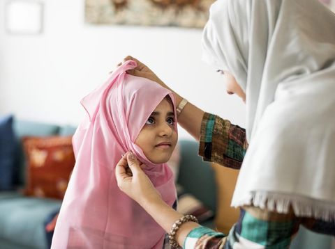 Muslim mom teaching daughter how to wear a Hijab