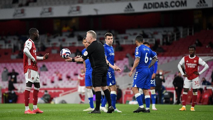 LONDON, ENGLAND - APRIL 23: Referee Jonathan Moss takes the ball off Nicolas Pepe of Arsenal after the penalty decision is overturned after a VAR review for offside during the Premier League match between Arsenal and Everton at Emirates Stadium on April 23, 2021 in London, England. Sporting stadiums around the UK remain under strict restrictions due to the Coronavirus Pandemic as Government social distancing laws prohibit fans inside venues resulting in games being played behind closed doors. (Photo by Michael Regan/Getty Images)