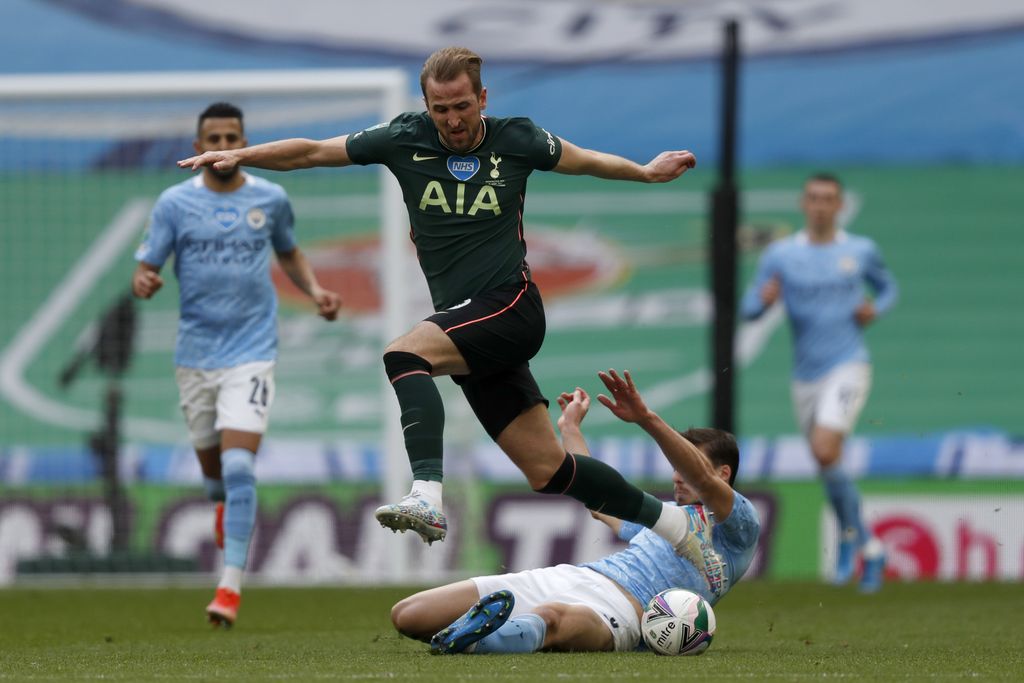 Manchester City's Ruben Dias, on the ground, tackles Tottenham's Harry Kane during the English League Cup final soccer match between Manchester City and Tottenham Hotspur at Wembley stadium in London, Sunday, April 25, 2021. (AP Photo/Alastair Grant)