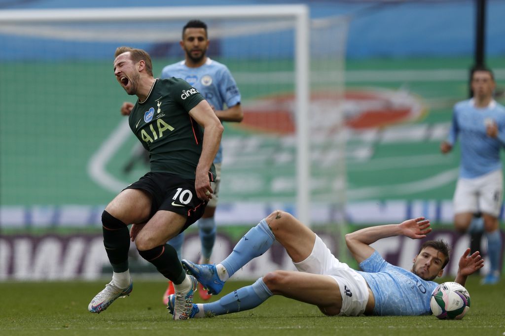 Manchester City's Ruben Dias, on the ground, tackles Tottenham's Harry Kane during the English League Cup final soccer match between Manchester City and Tottenham Hotspur at Wembley stadium in London, Sunday, April 25, 2021. (AP Photo/Alastair Grant)
