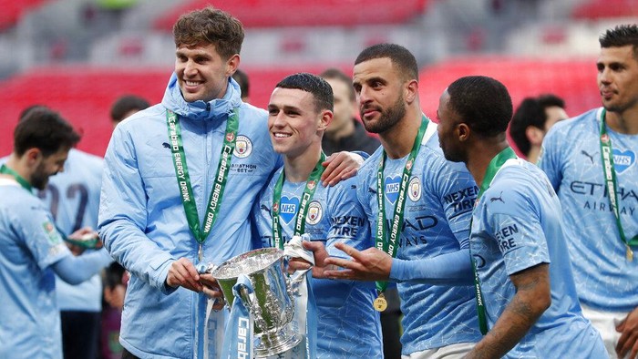 Manchester City players John Stones, Phil Foden, Kyle Walker and Raheem Sterling, from left to right, pose with the trophy at the end of the English League Cup final soccer match between Manchester City and Tottenham Hotspur at Wembley stadium in London, Sunday, April 25, 2021. Manchester City won 1-0. (AP Photo/Alastair Grant)