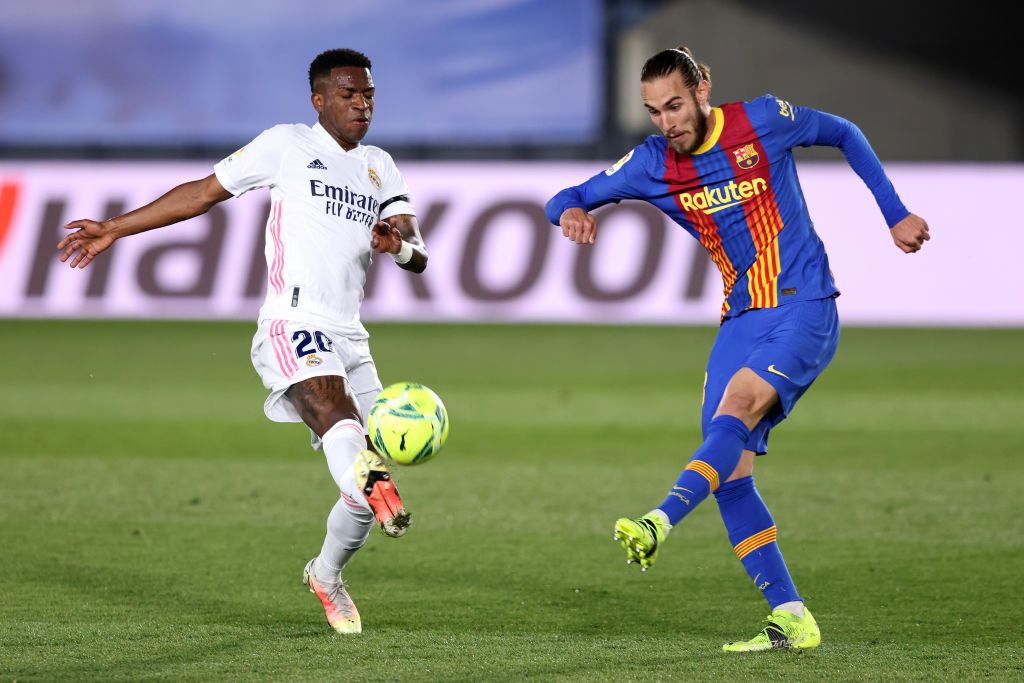 MADRID, SPAIN - APRIL 10: Oscar Mingueza of FC Barcelona is challenged by Vinicius Junior of Real Madrid  during the La Liga Santander match between Real Madrid and FC Barcelona at Estadio Alfredo Di Stefano on April 10, 2021 in Madrid, Spain. Sporting stadiums around Spain remain under strict restrictions due to the Coronavirus Pandemic as Government social distancing laws prohibit fans inside venues resulting in games being played behind closed doors.  (Photo by Angel Martinez/Getty Images)