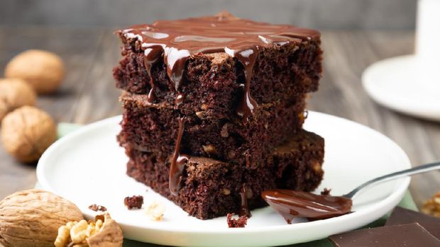 Chocolate spongy brownie cakes with walnuts and melted chocolate topping on a stack