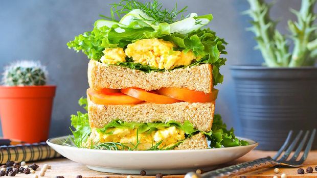 Scrambled eggs sandwich breakfast with fresh tomato sliced, cucumber sliced and green lettuce in front view for healthy breakfast concept.