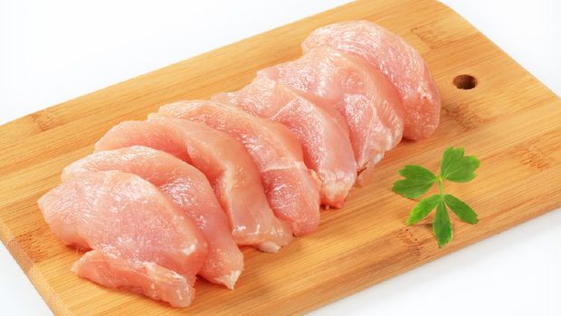 slices of fresh chicken fillet on the wooden cutting board