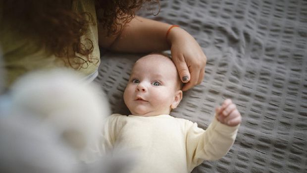 Funny photo of a cute little baby boy laying next to his mom