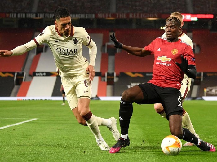 MANCHESTER, ENGLAND - APRIL 29: Paul Pogba of Manchester United battles for possession with Chris Smalling of Roma during the UEFA Europa League Semi-final First Leg match between Manchester United and AS Roma at Old Trafford on April 29, 2021 in Manchester, England. Sporting stadiums around Europe remain under strict restrictions due to the Coronavirus Pandemic as Government social distancing laws prohibit fans inside venues resulting in games being played behind closed doors. (Photo by Michael Regan/Getty Images)