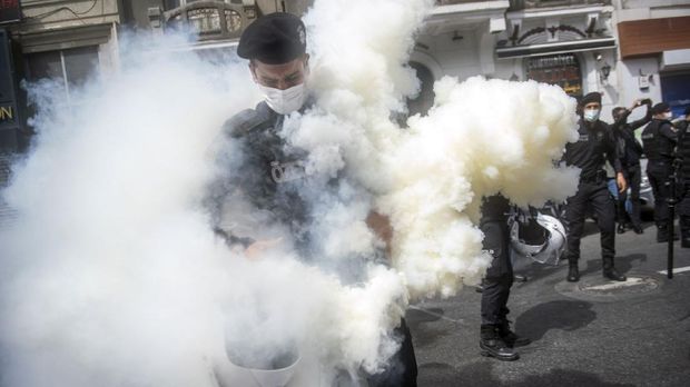 A Turkish policeman stands in a cloud of teargas after he accidentally let off a canister during a May Day rally marking the international day of the worker in Istanbul, on May 1, 2021. - With the highest infection rate in Europe, Turkey enters a full lockdown until May 17, with all non-essential businesses to close and travel between regions restricted. Alcohol sales at groceries and chain stores will be banned to prevent unfair competition with closed small liquor stores. (Photo by BULENT KILIC / AFP)