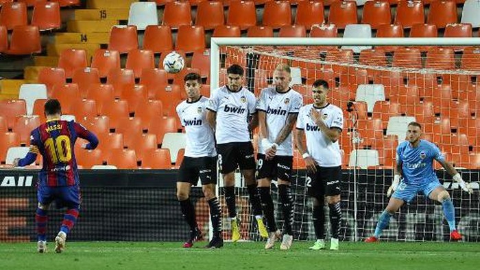 Barcelonas Argentinian forward Lionel Messi (L) scores his second goal during the Spanish League football match between Valencia and Barcelona at the Mestalla stadium in Valencia on May 2, 2021. (Photo by JOSE JORDAN / AFP)