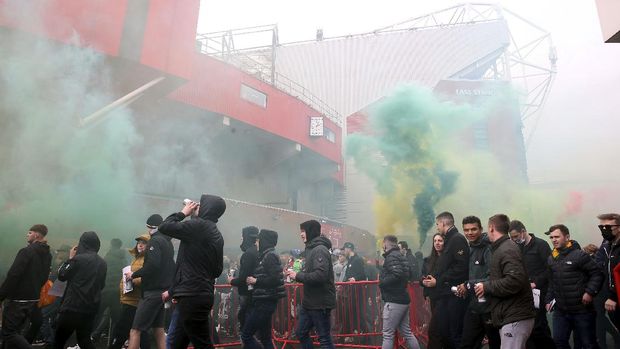 Fans make their way past barriers outside the ground as they let off flares whilst protesting against the Glazer family, owners of Manchester United, before their Premier League match against Liverpool at Old Trafford, Manchester, England, Sunday, May 2, 2021. (Barrington Coombs/PA via AP)