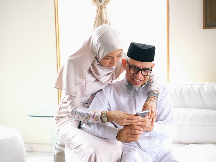 Father and daughter looking at phone during raya celebration in Malaysia