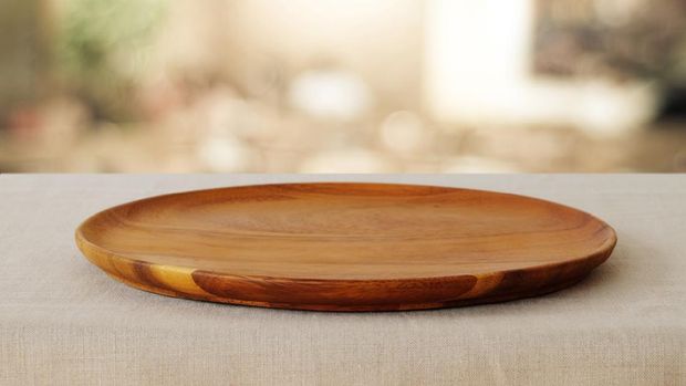 Empty wooden round tray over blurred cafe with bokeh light background, food and product display montage