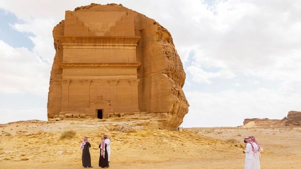 AlUla, Saudi Arabia, February 19 2020: Tourists from Saudi Arabia stand with ther guides in front of the tomb of Lihyan son of Kuza, known as Qasr AlFarid, the most iconic tomb in AlUla in the region of Mada’in Saleh, Saudi Arabia