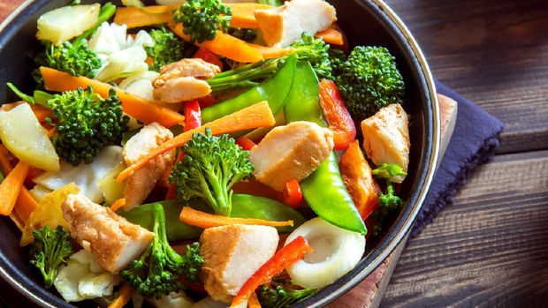 Healthy stir fried vegetables with chicken on pan close up
