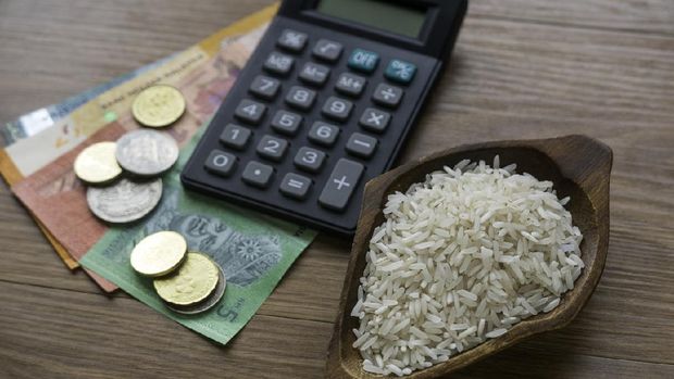 Selective focus of rice, money, coins and calculator on wooden background.