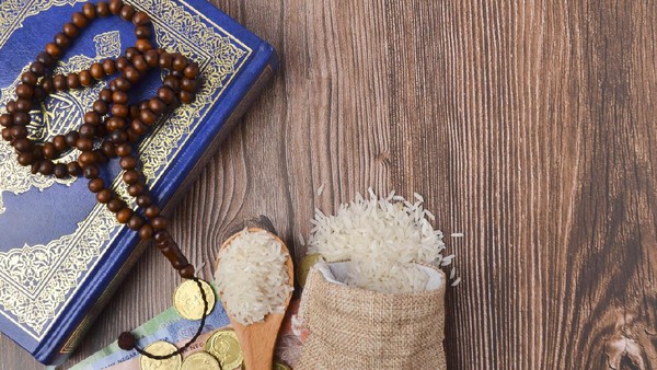 Coins, rosary, Holy Quran and rice in the sack. Zakat concept. Zakat is a form of alm-giving as a religious obligation or tax. Large Arab word right method to read correctly.