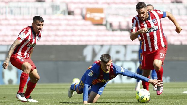Barcelona's Clement Lenglet, center, fights for the ball with Atletico Madrid's Koke, right, and Atletico Madrid's Angel Correa during the Spanish La Liga soccer match between FC Barcelona and Atletico Madrid at the Camp Nou stadium in Barcelona, Spain, Saturday, May 8, 2021. (AP Photo/Joan Monfort)