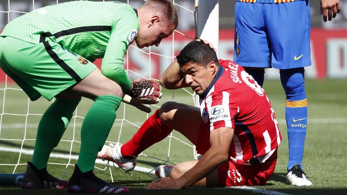 Barcelonas goalkeeper Marc-Andre ter Stegen, left, helps Atletico Madrids Luis Suarez during the Spanish La Liga soccer match between FC Barcelona and Atletico Madrid at the Camp Nou stadium in Barcelona, Spain, Saturday, May 8, 2021. (AP Photo/Joan Monfort)
