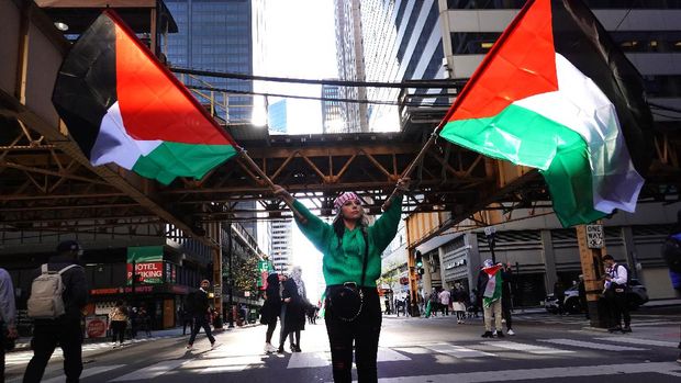 CHICAGO, ILLINOIS - MAY 12: A demonstrator waves Palestinian flags as she leads thousands marching through downtown toward the Israeli consulate to protest Israeli airstrikes in the Gaza Strip on May 12, 2021 in Chicago, Illinois. The death toll in Gaza continues to rise as the region is seeing the worst outbreak of violence since the 2014 Gaza war.   Scott Olson/Getty Images/AFP (Photo by SCOTT OLSON / GETTY IMAGES NORTH AMERICA / Getty Images via AFP)